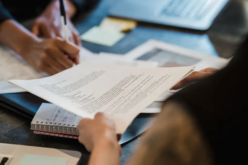Revisión de documentación y firma de un acuerdo de colaboración sobre una mesa
