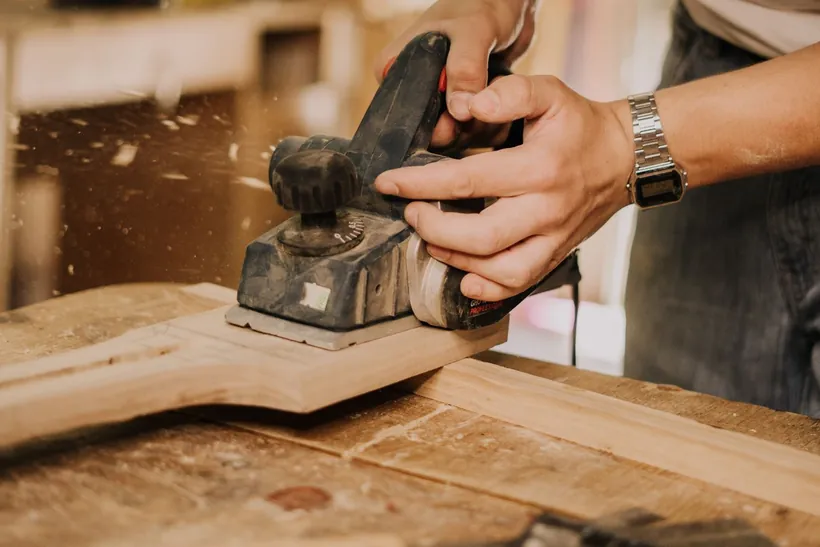 Carpintero trabajando la madera con cepillo manual en el taller